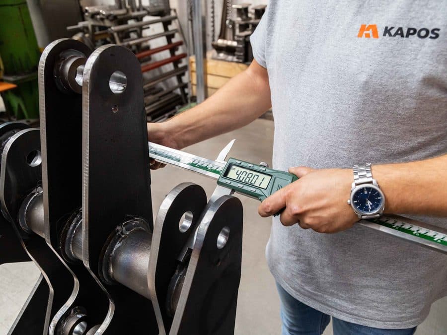 Kapos Atlas employee measuring a finished linkage component with a caliper