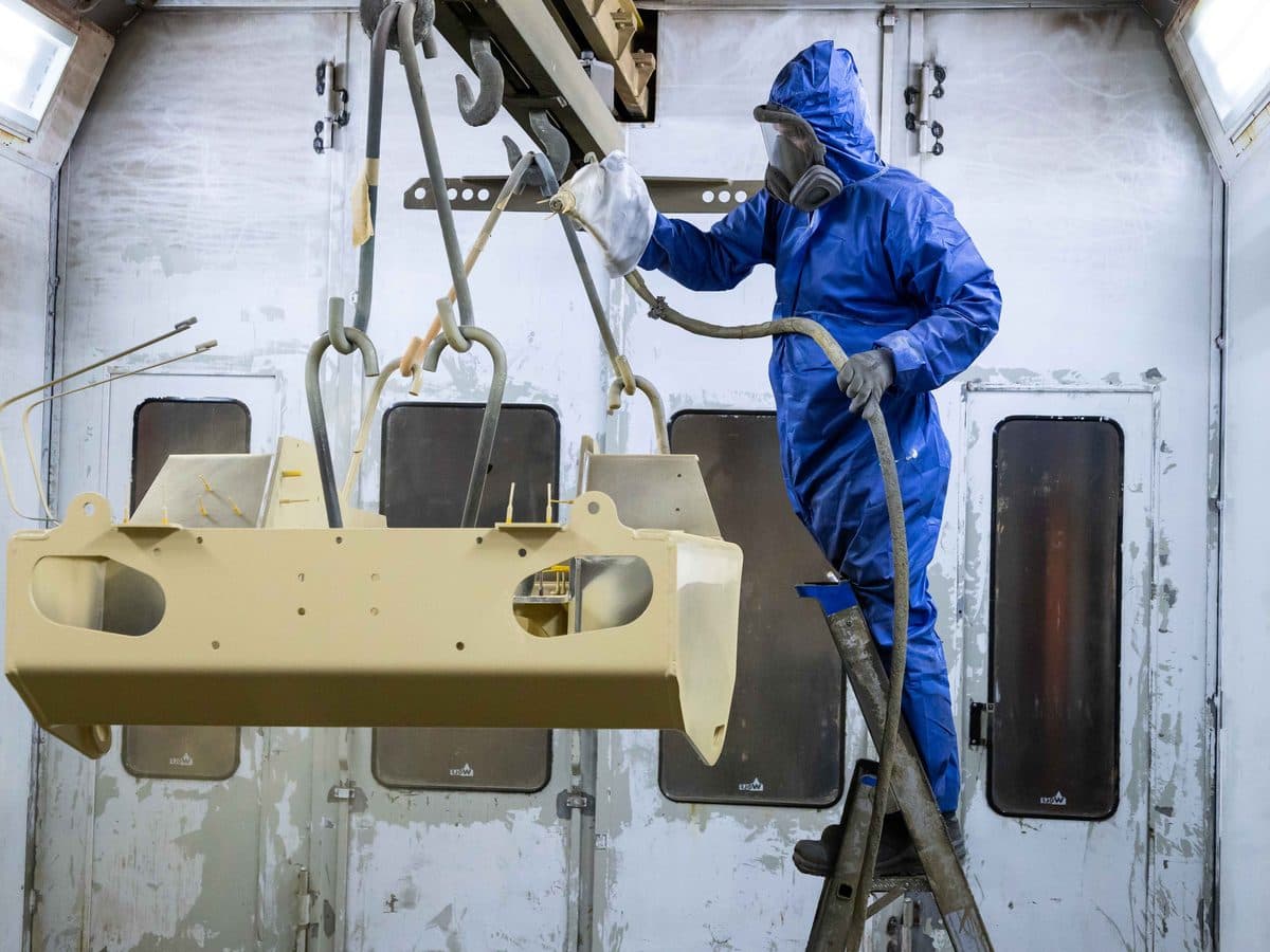 Kapos Atlas worker painting a steel component in the coating booth